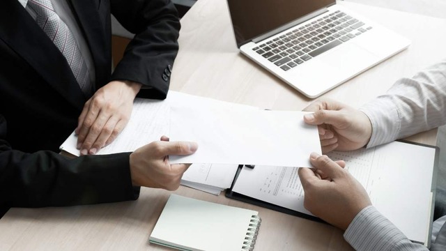 a person handing another person a paper at a meeting